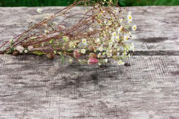 Field bouquet of flowers on the old wooden table, background