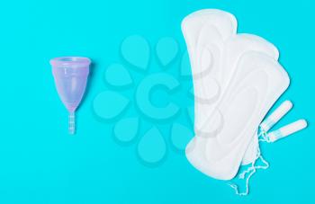 Pad, menstrual cup, tampon on a blue background. The view is flat. Concept of critical days, menstruation