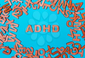 Word ADHD from wooden letters on a blue background. attention deficit hyperactivity disorder handwritten