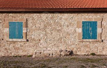 Antique stone wall and two blue wooden window shutters. Traditional vintage walnut, cypriot european style