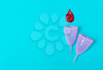 Two pink menstrual cup on a blue background. Concept of women's health, hygienic means of protection, menstruation, ecology of the planet.