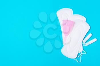 Pad, menstrual cup, tampon on a blue background. The view is flat. Concept of critical days, menstruation