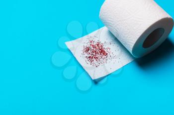Hemorrhoids treatment concept, toilet paper with blood on a blue background
