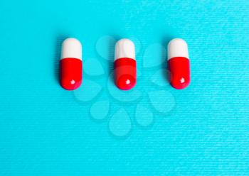White red capsules, pills on a blue background. Treatment concept