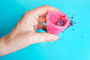 Female hand with a menstrual cup on a blue background. Concept of women's health, hygienic means of protection, menstruation, ecology of the planet.
