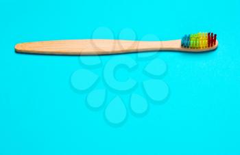 Eco bamboo toothbrush, organic on a blue background of colored bristles.  view i flat, from above. Concept of protection of nature, the environment.