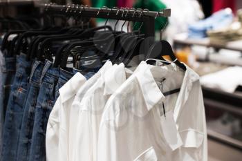 Women's clothes, fashionable, stylish on hangers in stores. Shopping Concept, Sales.Jeans and White Shirts