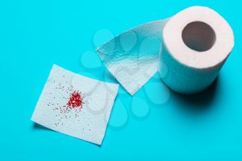 Hemorrhoids treatment concept, toilet paper with blood on a blue background