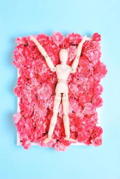 Wooden mannequin on a background of flowers. The concept of art, creativity, joy, happiness