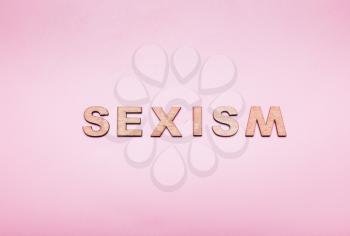 The word sexism in wooden letters on a pink background