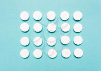 Round, white pills on a blue background. The concept of the treatment of the disease, healthcare, pharmaceuticals.