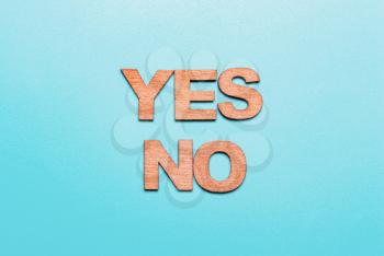 Words yes no in wooden letters on a blue background. The concept of choice, decision, consent, denial