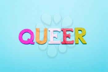 QUEER word from rainbow color letters on a blue background