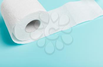 Close-up of a roll of white toilet paper on a blue background. Top view. The concept of hygiene, cleanliness