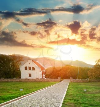 Road, bench, and house on the sunset. Landscape composition.
