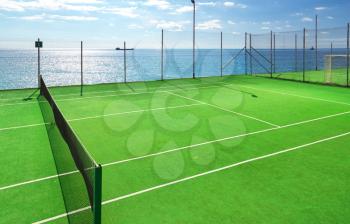 Green tennis court and blue sea. 