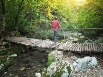 Man standing on the wood bridge in forest.