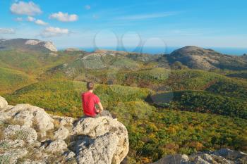 Man sitting on the edge of cliff mountain. Conceptual scene.