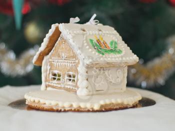 Gingerbread house over defocused lights of Chrismtas decorated fir tree
