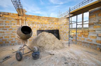 Home building. Concrete mixer and heap of sand. Architecture and industry composition.