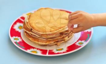 Child hand and pancakes in plate. Shallow depth-of-field