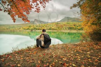 Man sitting alone on the pond. Conceptual nature and people scene. Autumn spring tume
