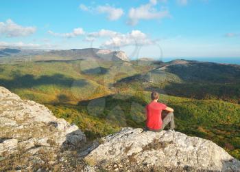 Man sitting on the edge of cliff mountain. Conceptual scene.