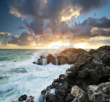 Storm seascape nature composition. Sea waves during storm on sunset splash on stones. 
