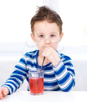 Little boy is drinking juice using straw
