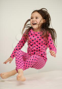 Cute happy girl jumping on the bed at home