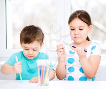 Little children is drawing on white paper using color pencils