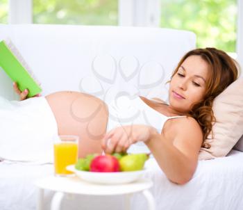 Happy pregnant woman with book