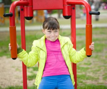 Cute happy girl is playing on playground, outdoor