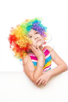 Cute girl in clown wig is holding blank banner, isolated over white