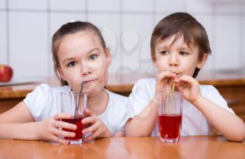 Cute little girl and boy drink juice