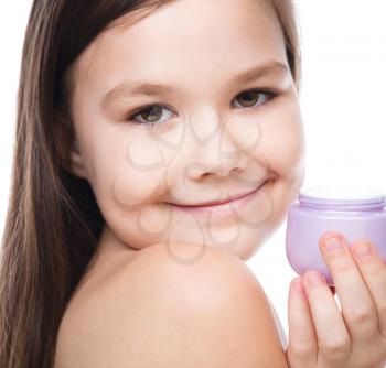 Beautiful girl applying moisturizer cosmetic cream on face, isolated over white