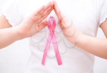 healthcare and medicine concept - womans hands holding pink breast cancer awareness ribbon