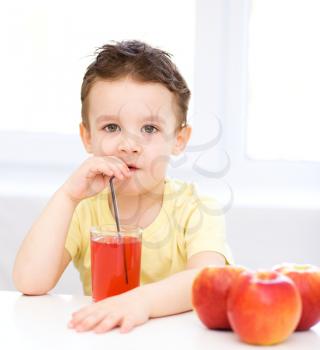 Little boy is drinking apple juice using straw