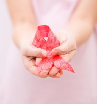 Healthcare and medicine concept - girl hands holding red breast cancer awareness ribbon