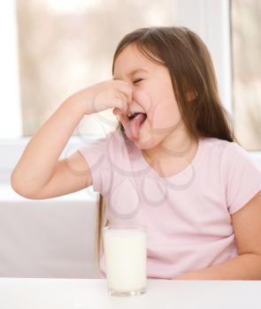 Sad little girl refuses to drink a glass of milk