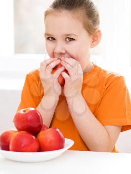 Portrait of a cute cheerful little girl with red apple