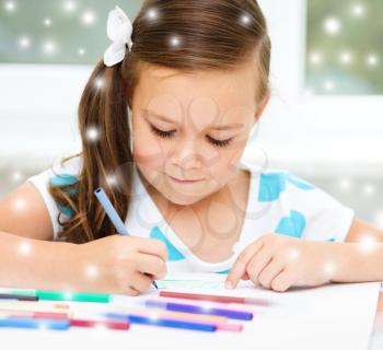 Cute girl is drawing using color pencils, over snowy background