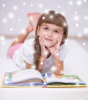 Cute little girl is reading a book, over snowy background