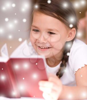 Cute little girl is reading a book, over snowy background