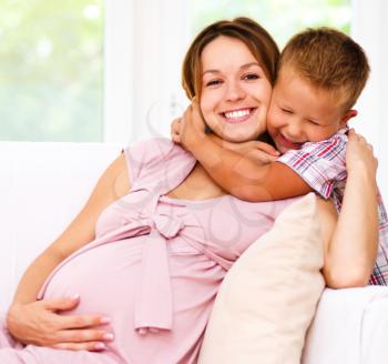 Happy child holding belly of pregnant woman, isolated over white
