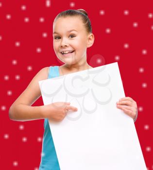 Cute girl is holding blank banner, over red snowy background