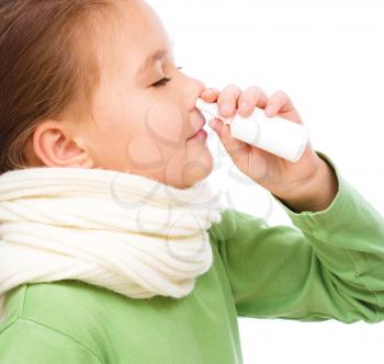 Cute girl spraying her nose with nasal spray, isolated over white