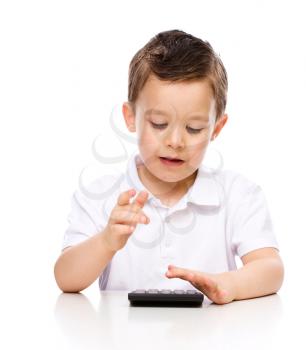 Cute boy is using calculator, isolated over white