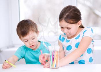 Little children is drawing on white paper using color pencils