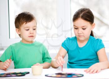 Little children are painting with paint, sitting at table